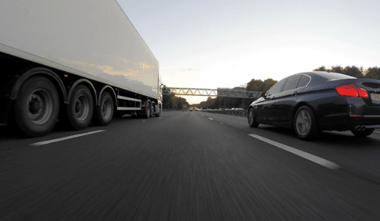 an 18 wheeler and a car driving on the freeway