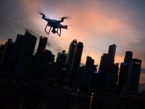 A drone flies at sunset over a city skyline.